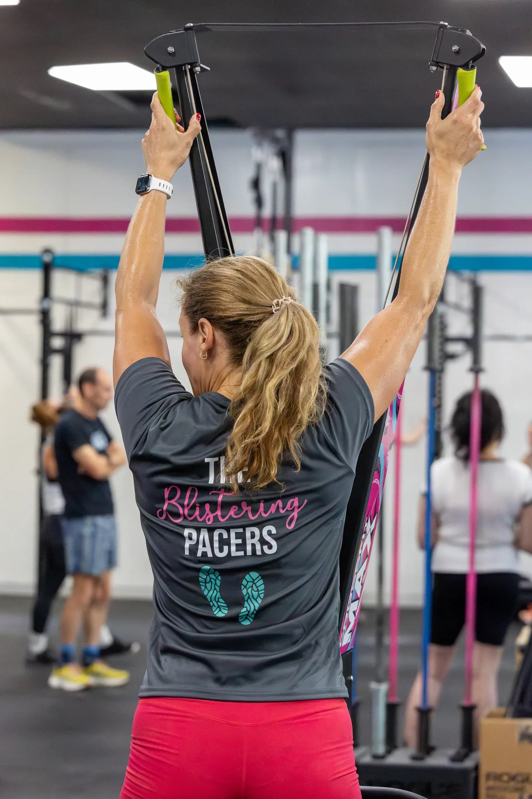 A member pulls the handles of a SkiErg during a workout.