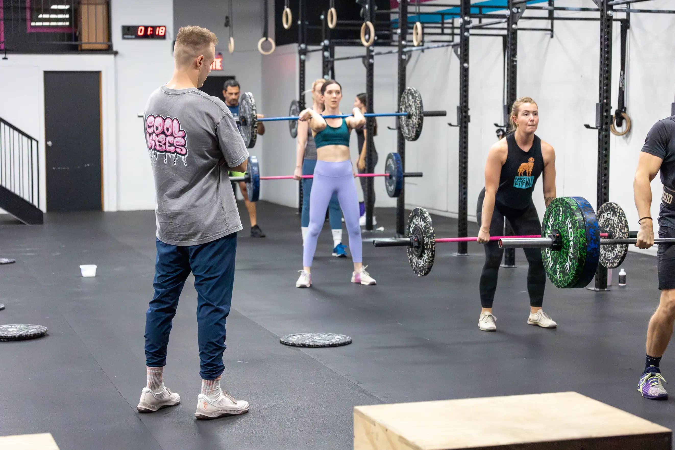 A coach watches members lift barbells during a class at CrossFit Max.