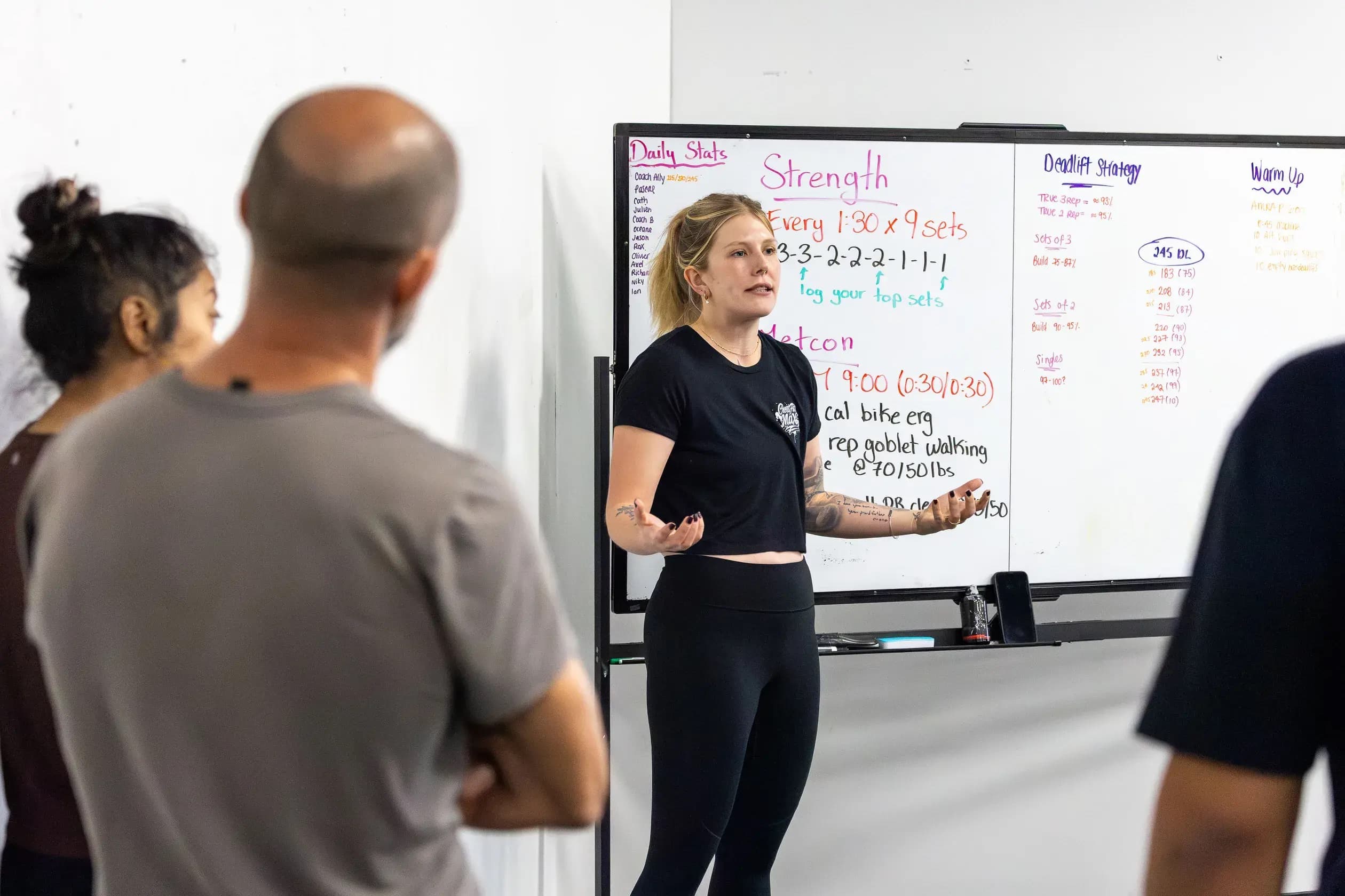 A coach explains the workout at the whiteboard before class.