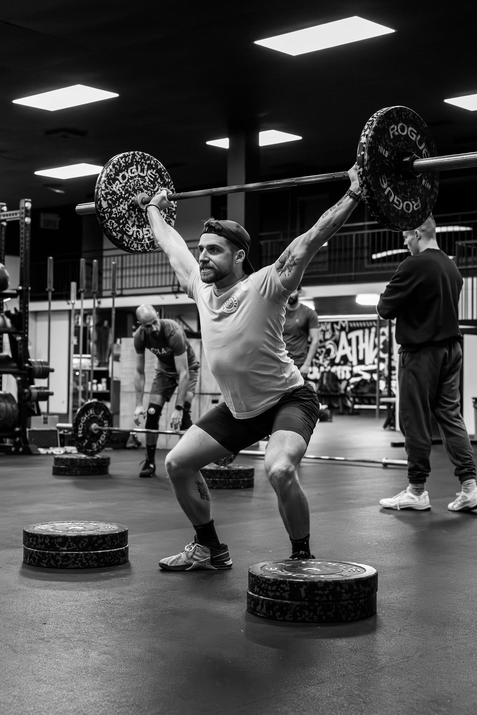 A member holding an overhead squat with a barbell during class.