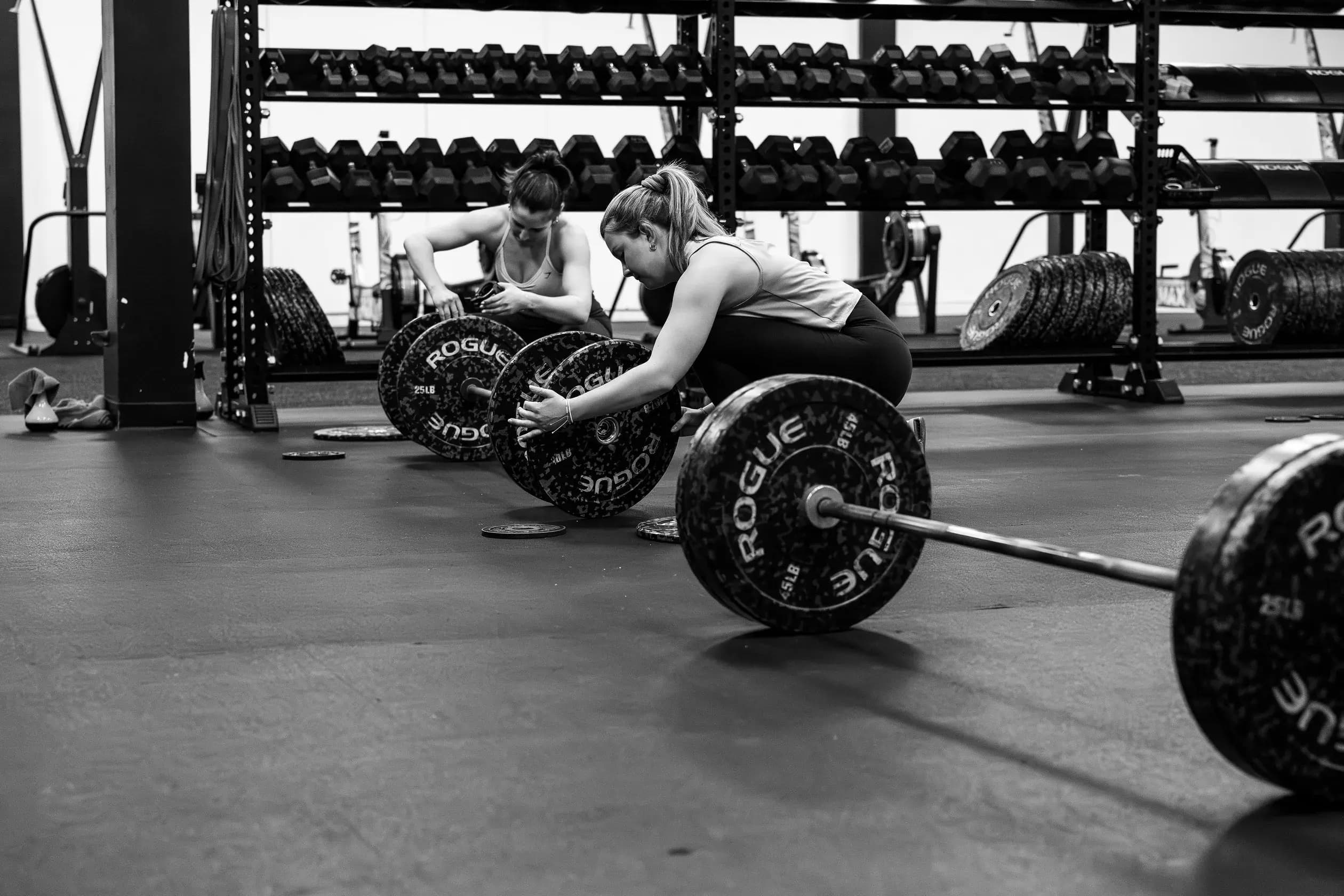 Two members load plates onto their barbells.